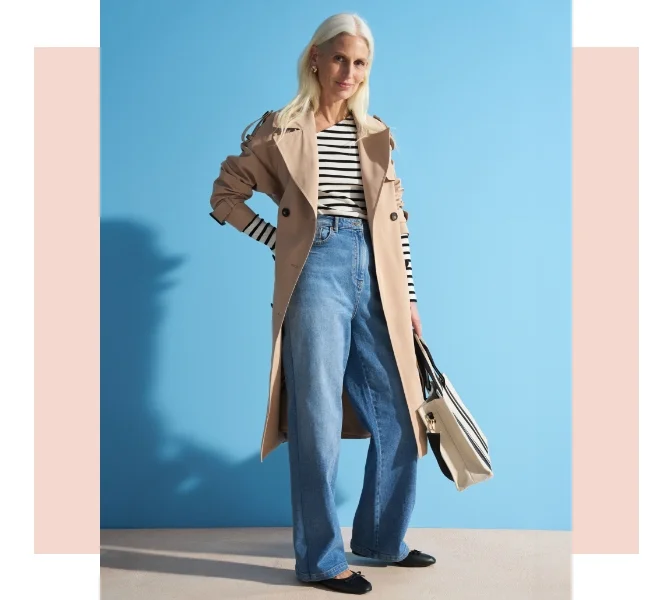 Woman wearing wide leg jeans, a striped long sleeve t shirt, a beige trench coat and ballet flats